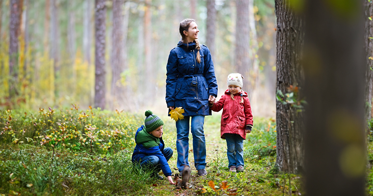 Bild på kvinna som går i skogen med två barn.