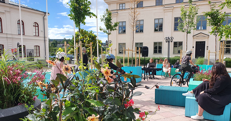 En bild över sommartorget i Härnösand. Turkosa och blå kuber att sitta på är utplacerade i olika storlekar. Vissa med färgglada blomsterarrangemang planterade.